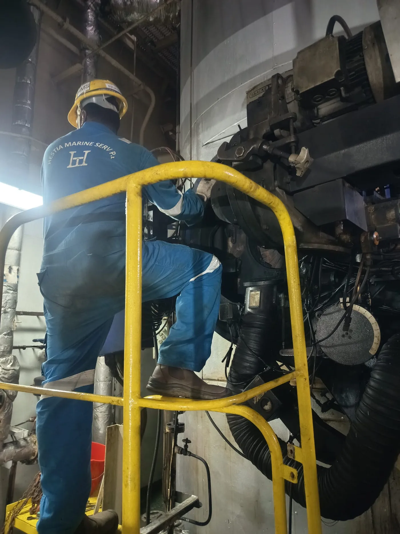 Hestia Marine Services technician climbing into an engine bay for maintenance work
